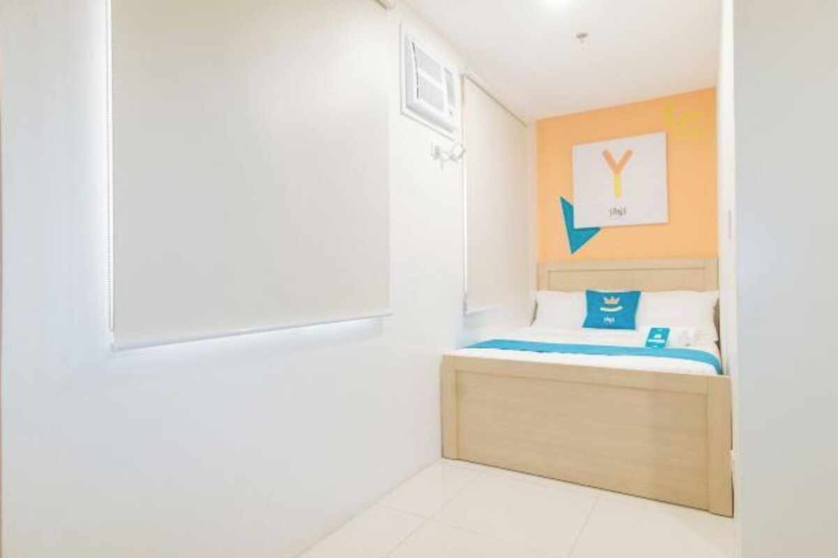 Un dormitorio con una cama, una obra de arte colgada en la pared y una puerta.