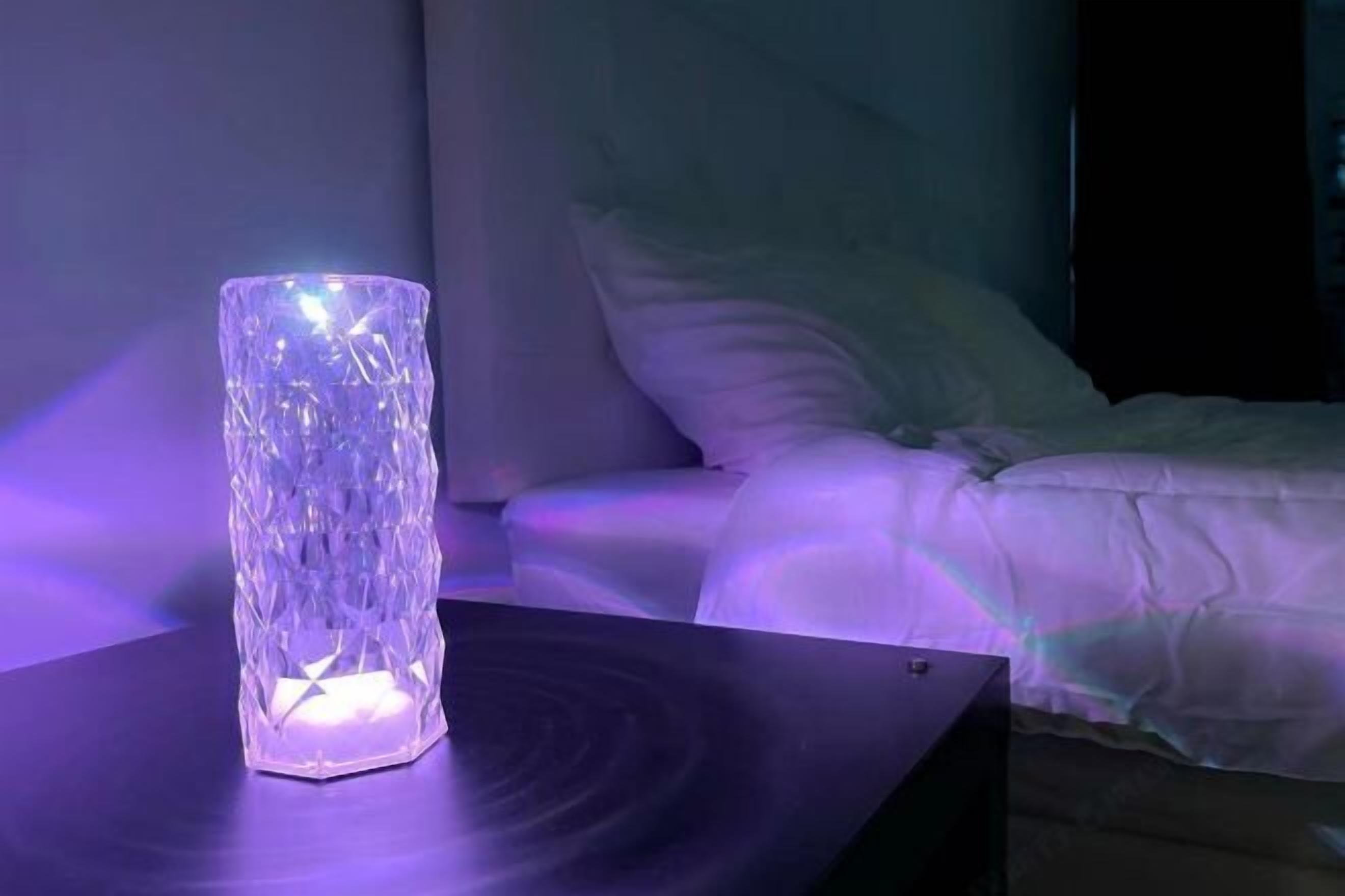 A room with a bed, a bedside table, and a decorative glass object on the table.