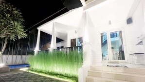 Una casa moderna con facciata bianca, un patio in pietra e una scala che conduce all'ingresso.