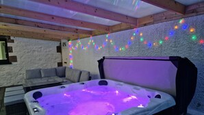 A hot tub with a canopy, a grey sofa, and colorful string lights on a textured wall. - Highland House in Ullapool (Ullapool)