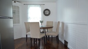 Uma sala de jantar com uma mesa redonda, quatro cadeiras e um relógio na parede.