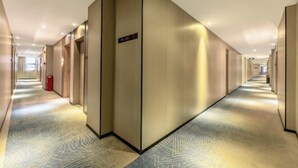 A long, narrow hotel corridor with a patterned carpet and a large, metallic elevator. - Bohan Hotel (Guangzhou Olympic Sports Center – Tangxia Metro Station Branch) (Guangzhou)