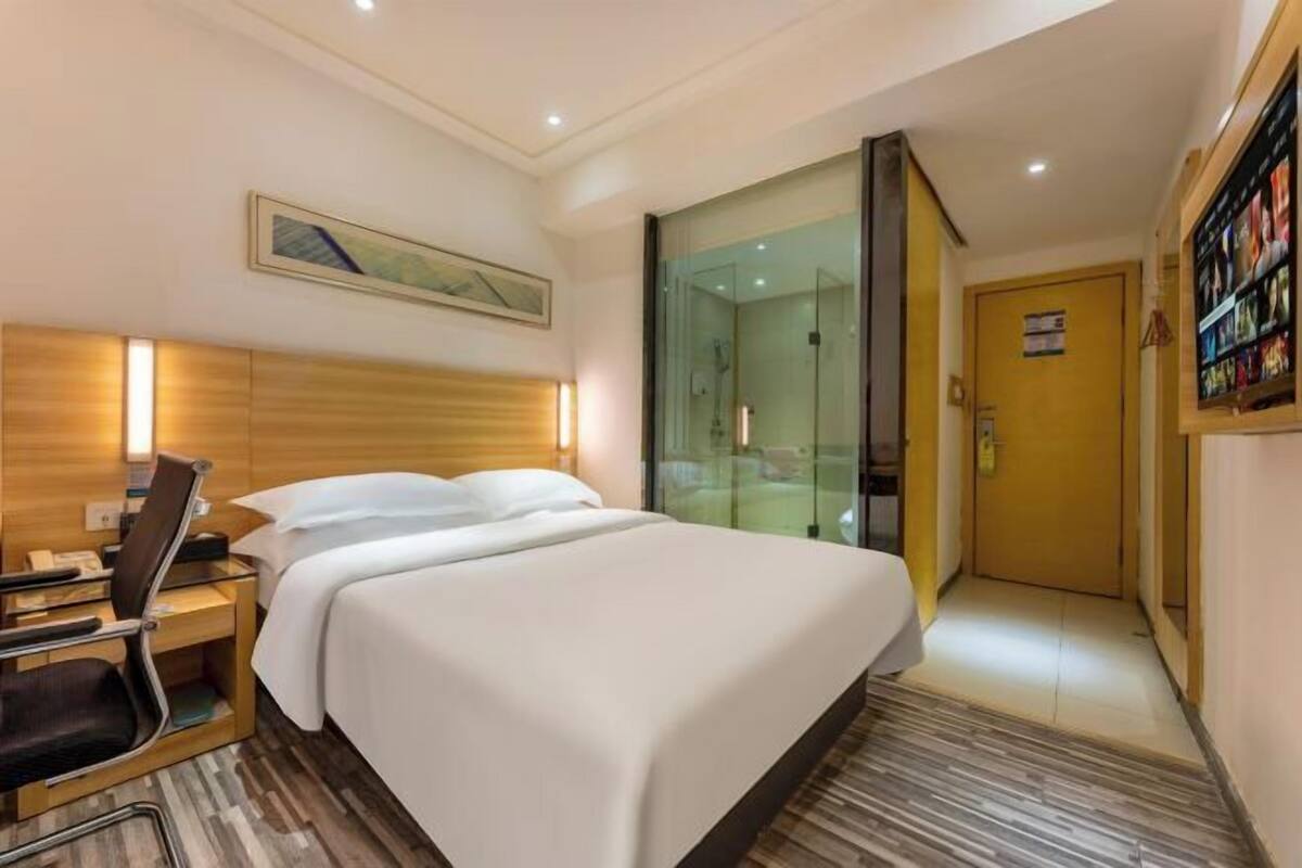 Ein Hotelzimmer mit Bett, Nachttisch, Stuhl und einer Duschkabine.