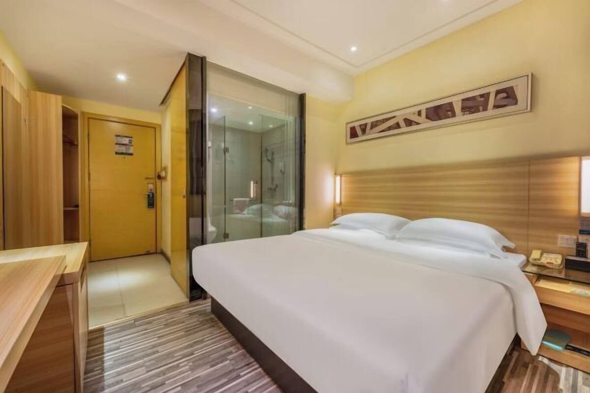 Ein Hotelzimmer mit einem Bett, einem Schreibtisch, einer Duschkabine aus Glas und einem Holzschrank.