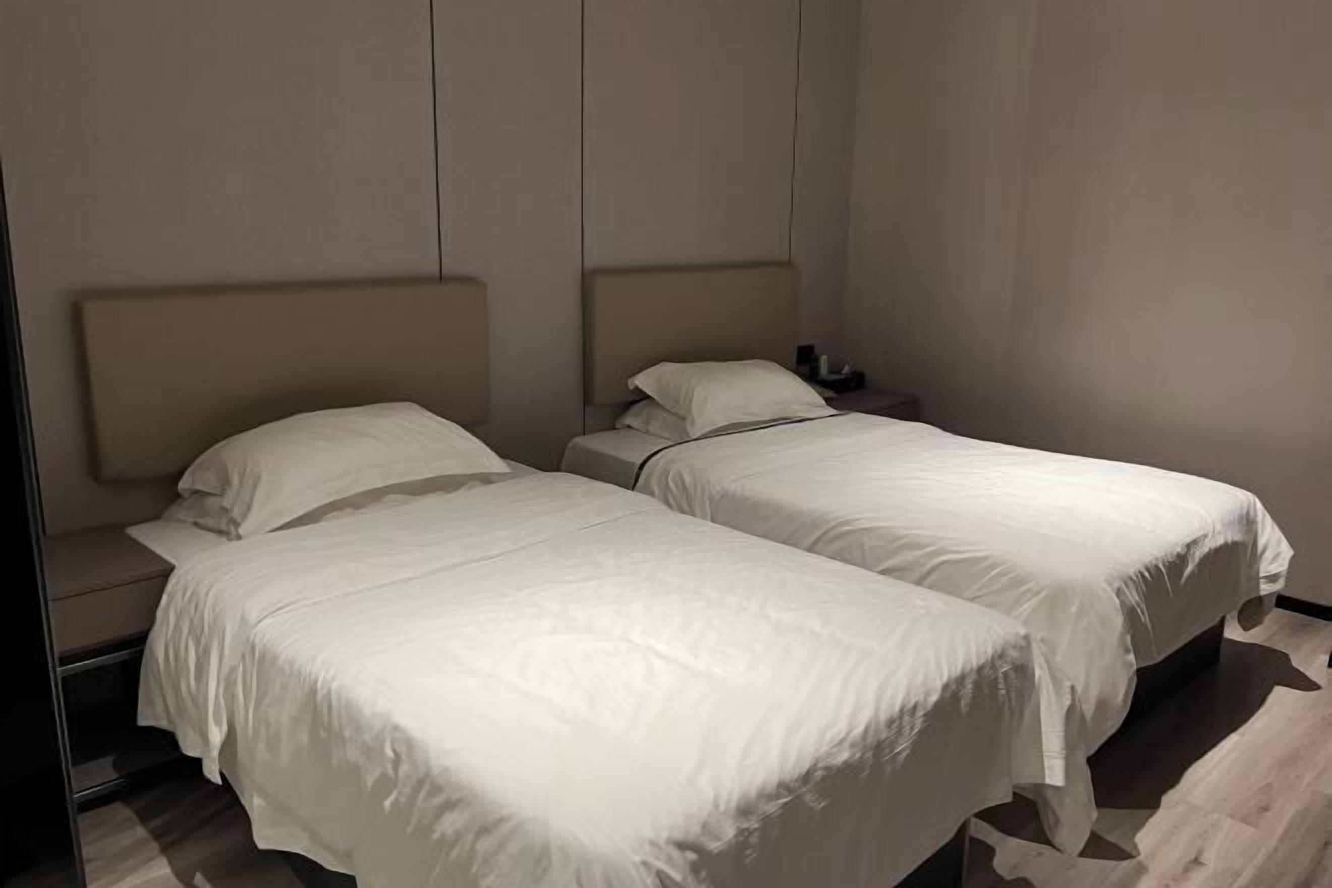 Habitación de hotel con dos camas, cada una con ropa blanca y cabeceros.