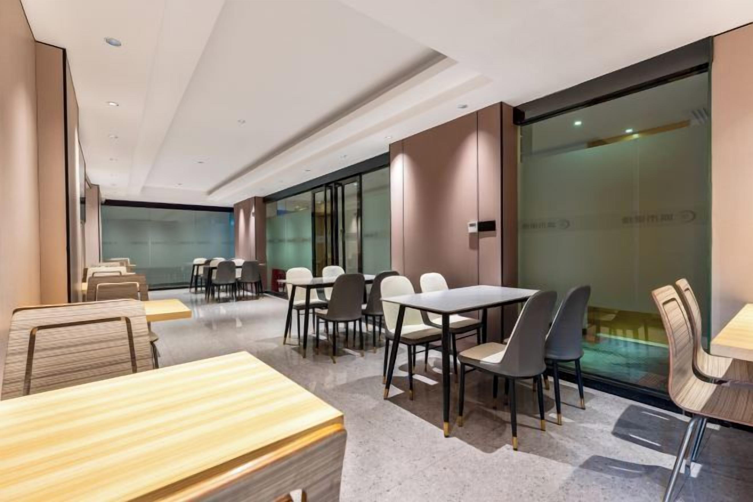 Una sala conferenze moderna in un hotel, con tavoli, sedie, pareti in vetro e vista sulla città.