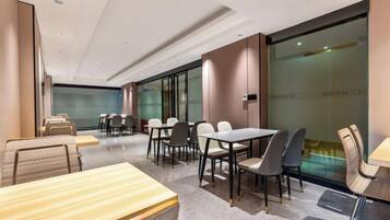 Una sala conferenze moderna in un hotel, con tavoli, sedie, pareti in vetro e vista sulla città.
