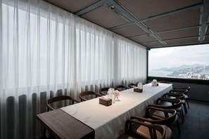 A conference room with a long table, chairs, a view of the city, and a window with curtains. - Bai Man Hotel (Guangzhou Financial City Tangxia Metro Station) (Guangzhou)