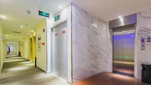 A hotel corridor with marble walls, an elevator, and a carpeted floor. - Bohan Hotel (Guangzhou Olympic Sports Center – Tangxia Metro Station Branch) (Guangzhou)