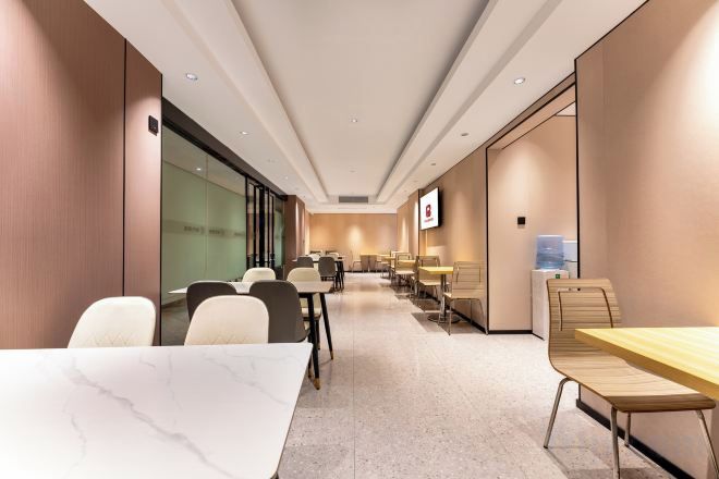 Un salón de conferencias de hotel con mesas y sillas, un dispensador de agua y una pantalla de televisión.