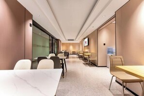Una sala de conferències d'hotel amb taules i cadires, un dispensador d'aigua i una pantalla de televisió.