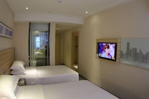 Une chambre d’hôtel avec deux lits, un téléviseur fixé au mur et une porte vitrée donnant sur la salle de bain.