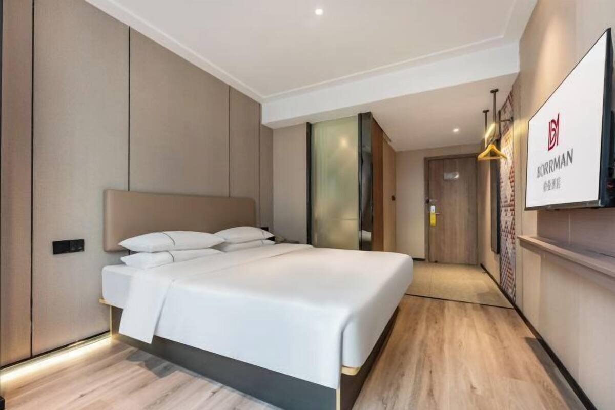 Ein modernes Hotelzimmer mit einem großen Bett, einem Flachbildfernseher und Holzboden.