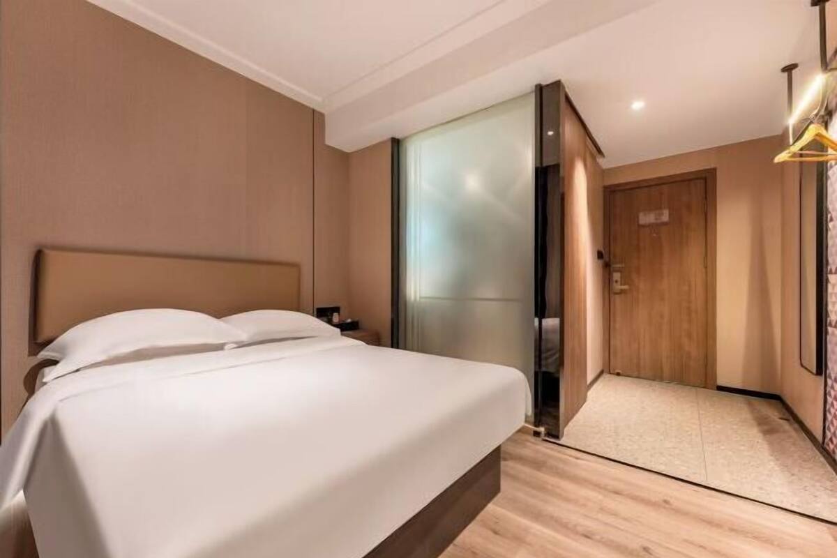 Ein Hotelzimmer mit Bett, einer Schiebetür, Holzboden und einer Wandleuchte.