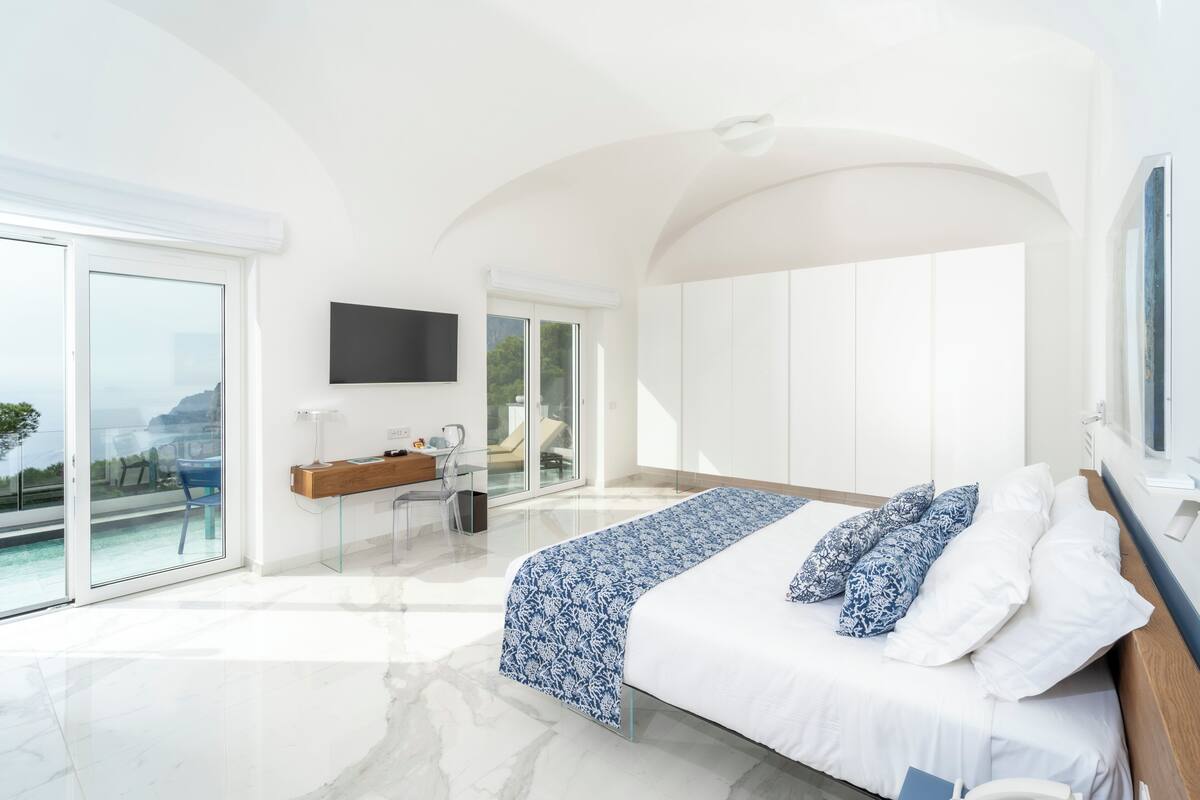Une chambre moderne avec un grand lit, un bureau et une vue sur l’océan.