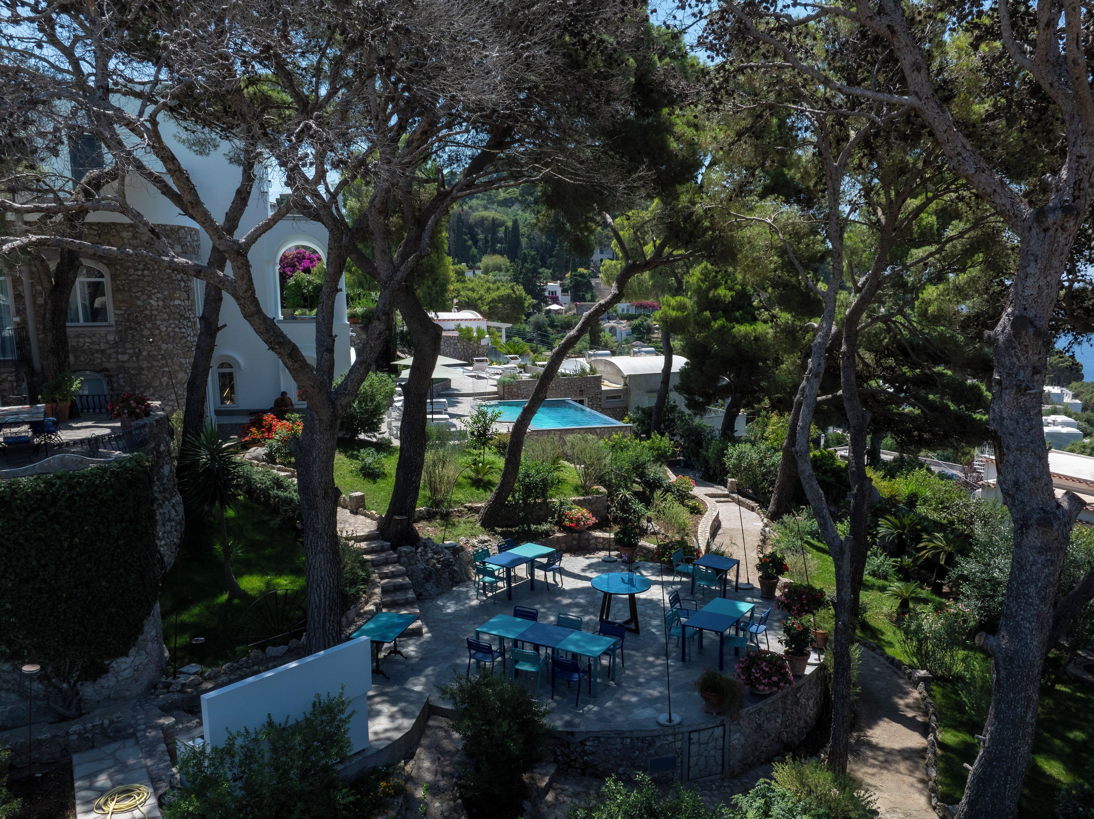 Un área junto a la piscina con mobiliario exterior y un edificio de piedra al fondo.