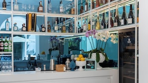 A bar area with shelves of liquor bottles, glasses, and decorative items. - Villa L'Ara (Capri)