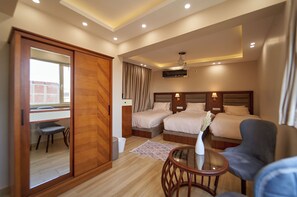 Ein Hotelzimmer mit zwei Betten, einem Schreibtisch, einem Stuhl, einem kleinen Tisch und einer Schiebetür.