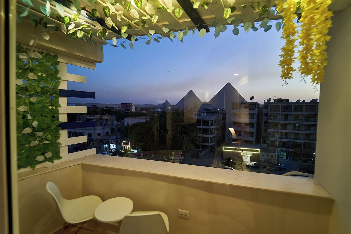 A balcony with a view of pyramids, a white chair, and a table.