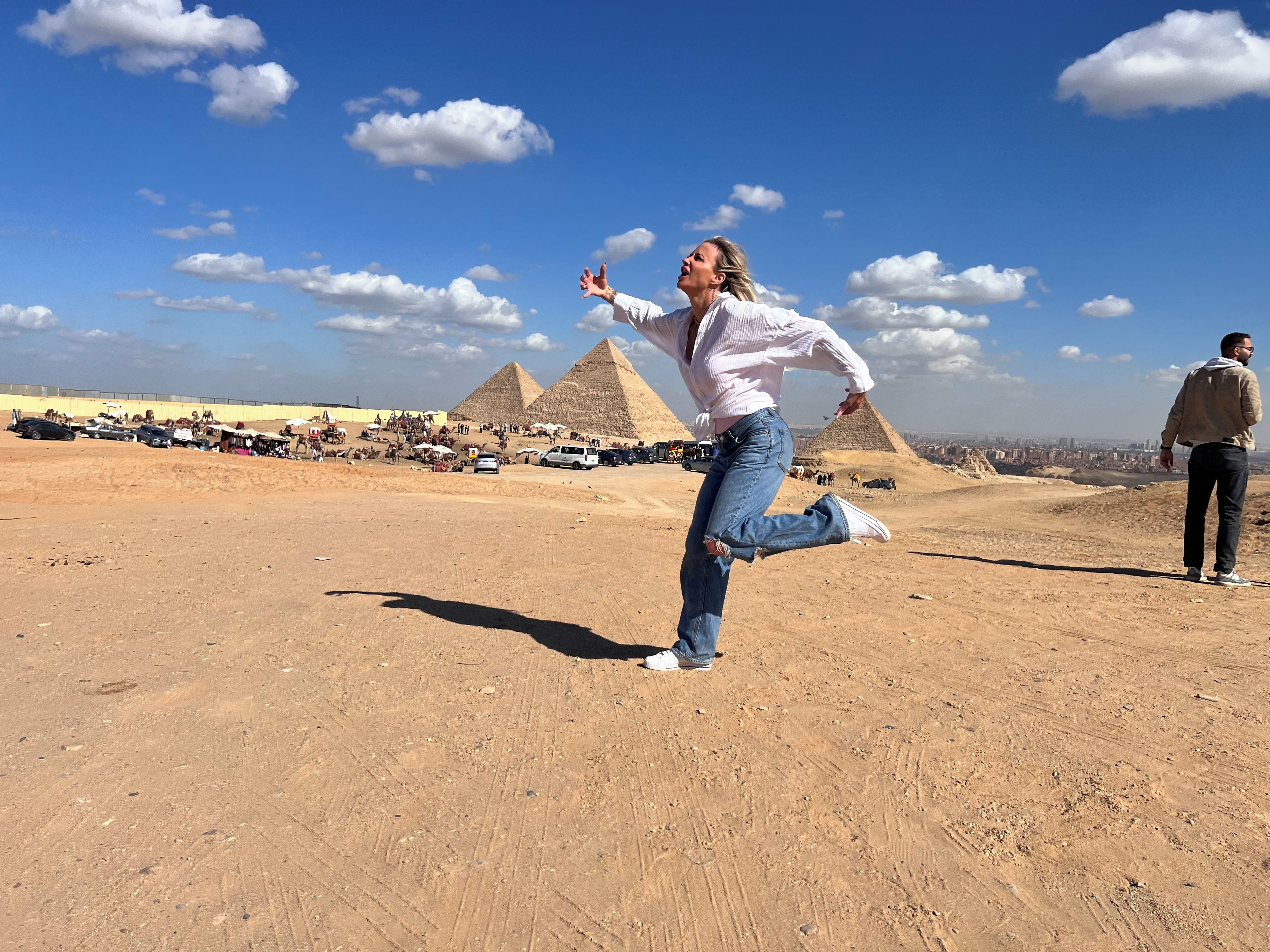 A desert landscape with pyramids in the background and a person in mid-action.