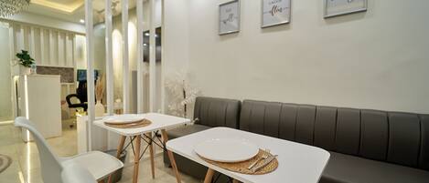 Un comedor moderno con una mesa blanca para dos, un sofá gris y una silla blanca.