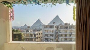 A balcony with two white chairs and a view of the pyramids in the background. - Prestige pyramids inn (Giza)