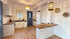 Una cuina moderna amb encimera de marbre, sòcols de fusta i il·luminació penjant.