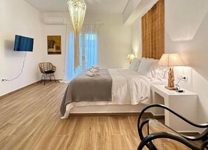 A modern bedroom with a bed, bedside table, lamp, and a chair.