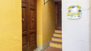 A yellow building with a wooden door and a small set of stairs leading to a door with a metal handle. - B&B Casa Decimo (Greve in Chianti)