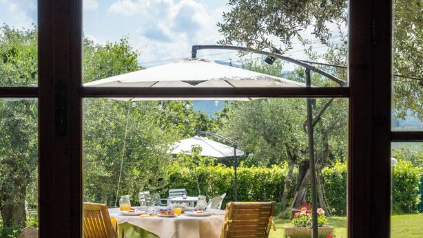 An outdoor dining area with a table set for four, surrounded by chairs, under a large umbrella. - B&B Casa Decimo (Greve in Chianti)