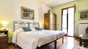 A bedroom with a bed, wooden floor, a wardrobe, a chair, and a painting on the wall. - B&B Casa Decimo (Greve in Chianti)