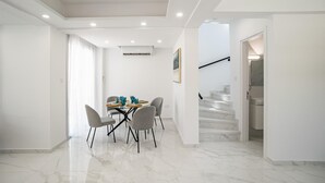 Ein modernes Wohnzimmer mit Essbereich, einer Treppe und einem Flur.