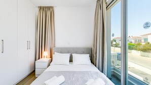 Ein Hotelzimmer mit einem großen Bett, zwei Nachttischen und Blick nach draußen.