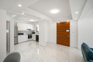 A modern kitchen with white cabinetry and a wooden door.