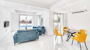 Ein modernes Wohnzimmer mit einem blauen Sofa, gelben Sesseln und einem Glastisch.