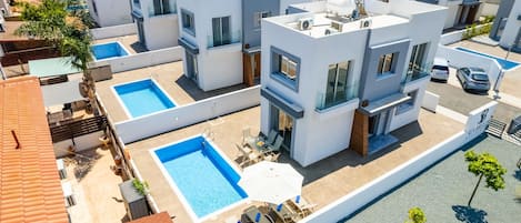 Un moderno complejo residencial con varios edificios, una piscina y un estacionamiento.