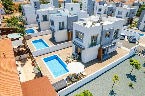 A modern residential complex with multiple buildings, a swimming pool, and a parking area.