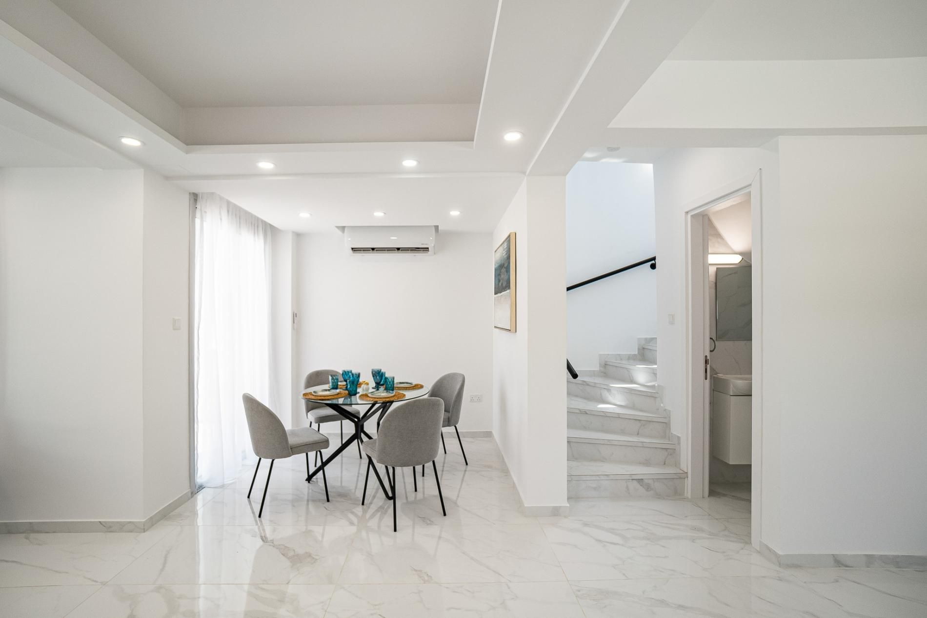 Un interior moderno con comedor, escalera y pasillo.