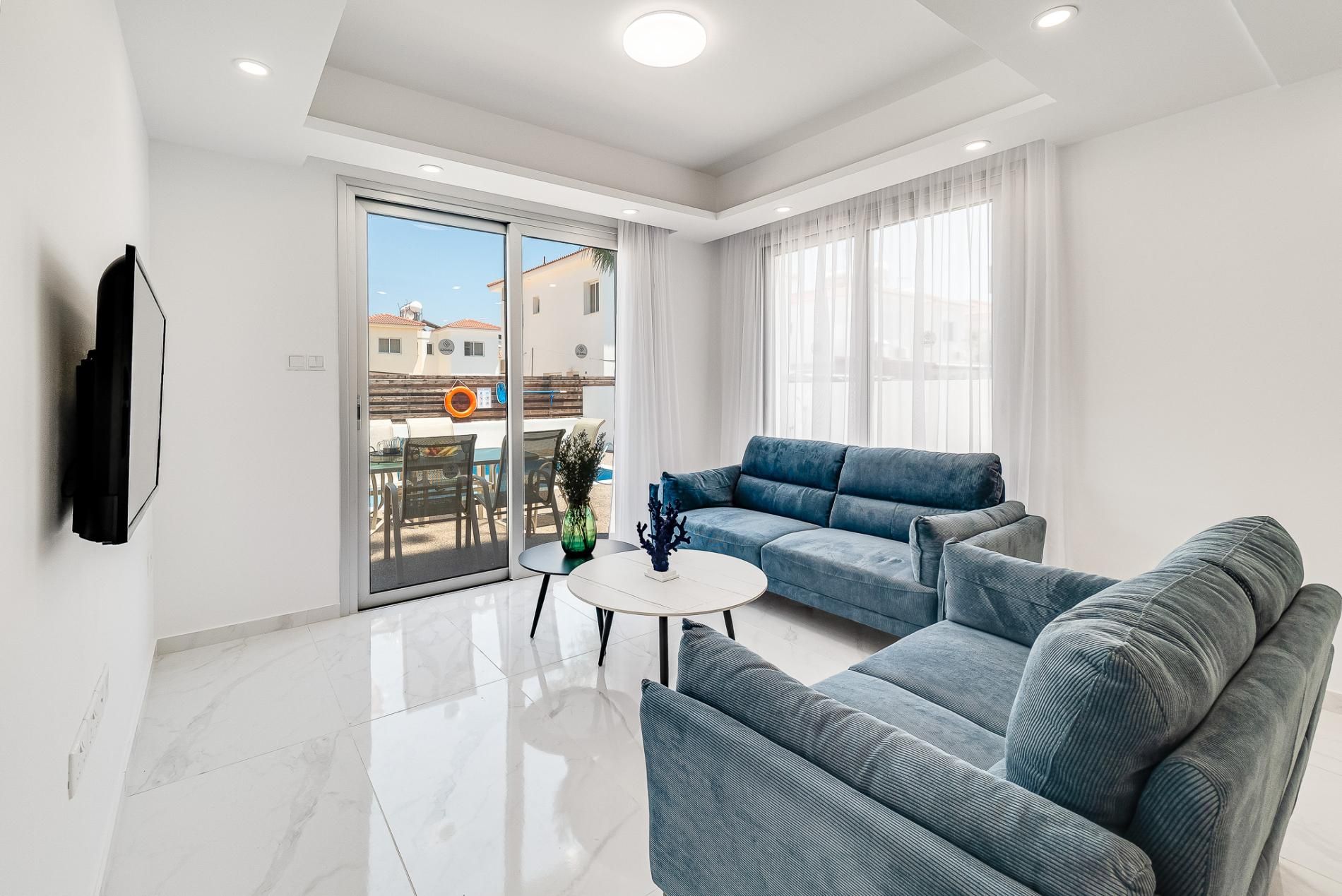 A modern living room with a sofa, a coffee table, and a TV mounted on the wall.
