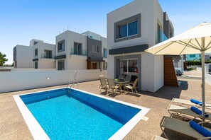 A modern residential building with a swimming pool and outdoor seating area.