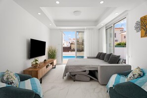 A modern bedroom with a TV, a bed, a sofa, and a view of the outside.