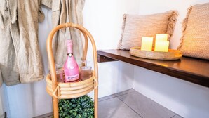 A wicker basket with a pink bottle and glasses, a wooden tray with candles, and a beige towel on a shelf. - Faro Escondido Pool&Jacuzzi OceanView in Fajardo (Fajardo)