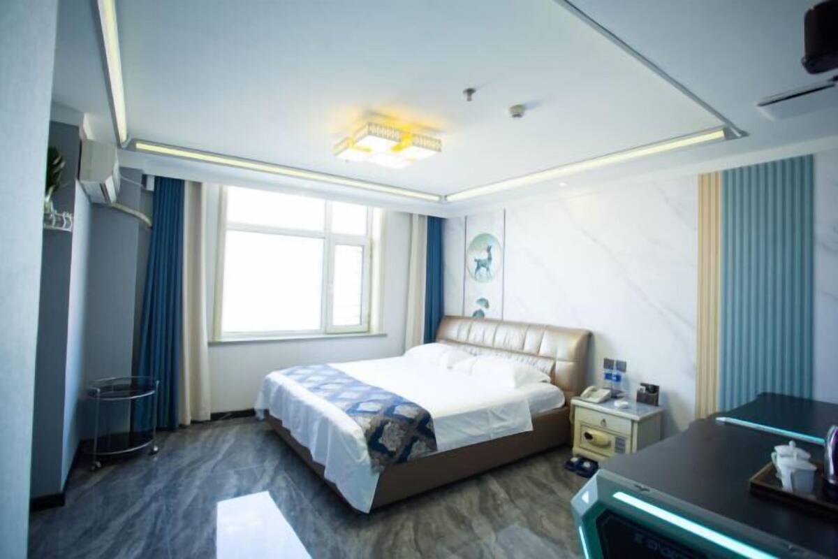 Een hotelkamer met een bed, nachtkastje, bureau en een raam.