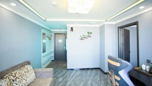 Een hotelkamer met een bank, een stoel, een bureau en een koelkast.