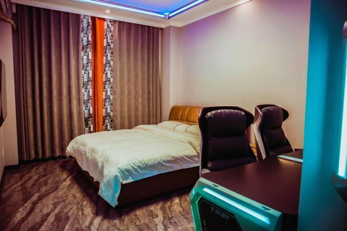 Een hotelkamer met een bed, twee stoelen, een bureau en een computer.
