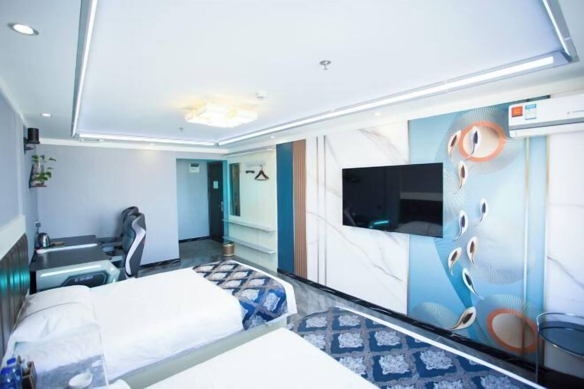 Een hotelkamer met een bed, een televisie, een spiegel en een muur met een rond ontwerp.