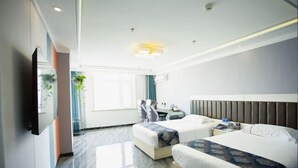 Een hotelkamer met twee bedden, een flatscreen-tv, een bureau en een raam met gordijnen.