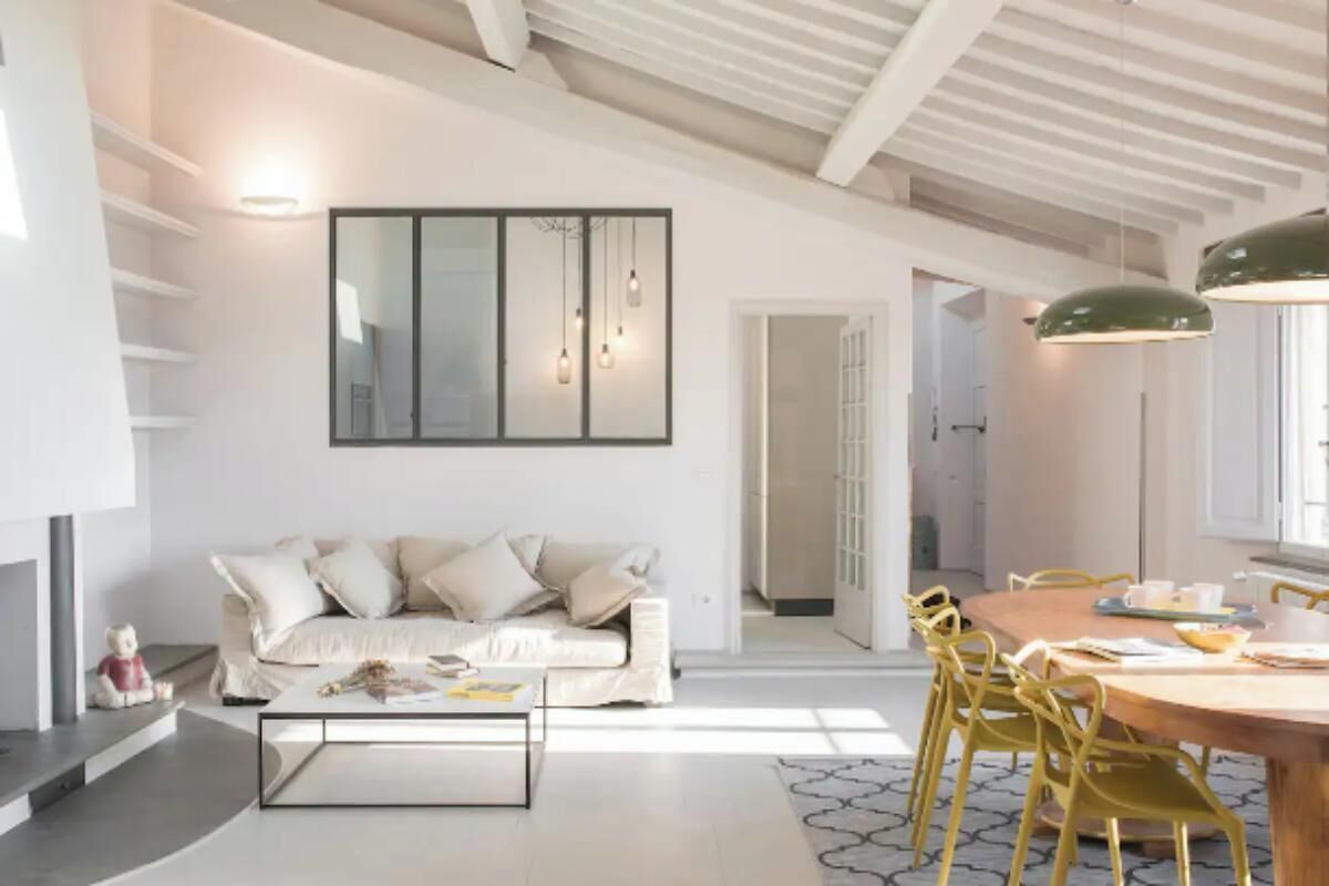 A modern living room with a sofa, coffee table, and dining area with chairs.