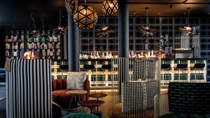 Un espace bar moderne, doté de sièges, d’un comptoir et d’un éclairage décoratif.