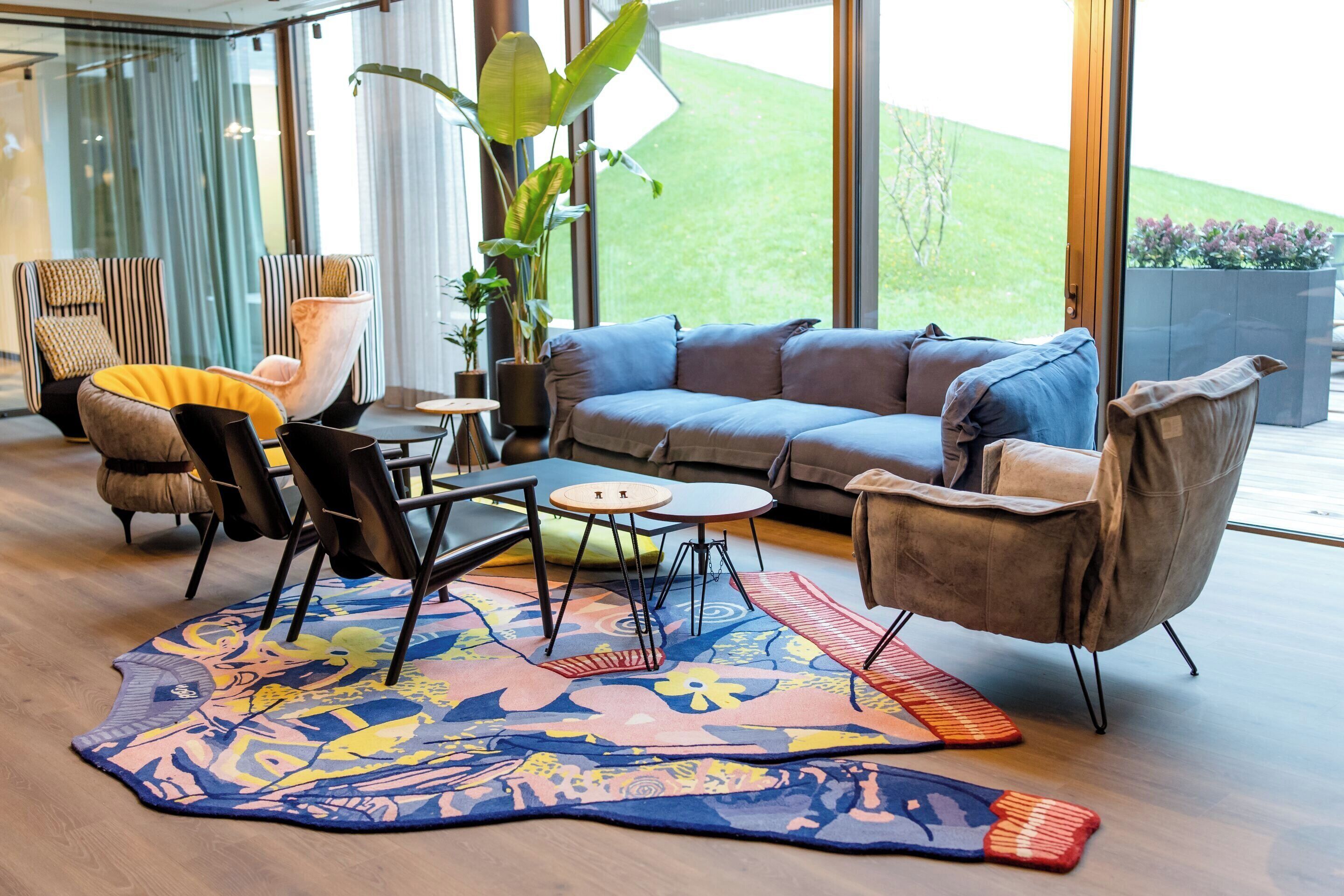 A modern living room with a sofa, chairs, a coffee table, and a patterned rug.
